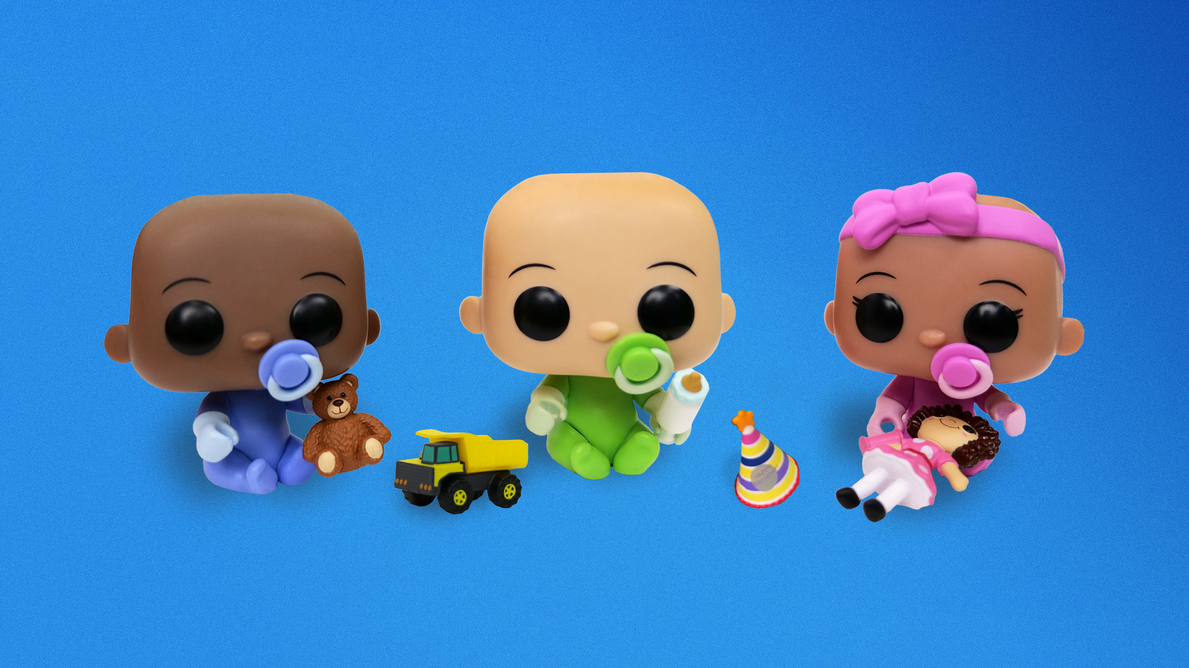 Three Pop! Yourself Babies of different skin tones, sit side by side with tiny accessories including a teddy bear, toy truck, bottle, birthday hat, and doll.